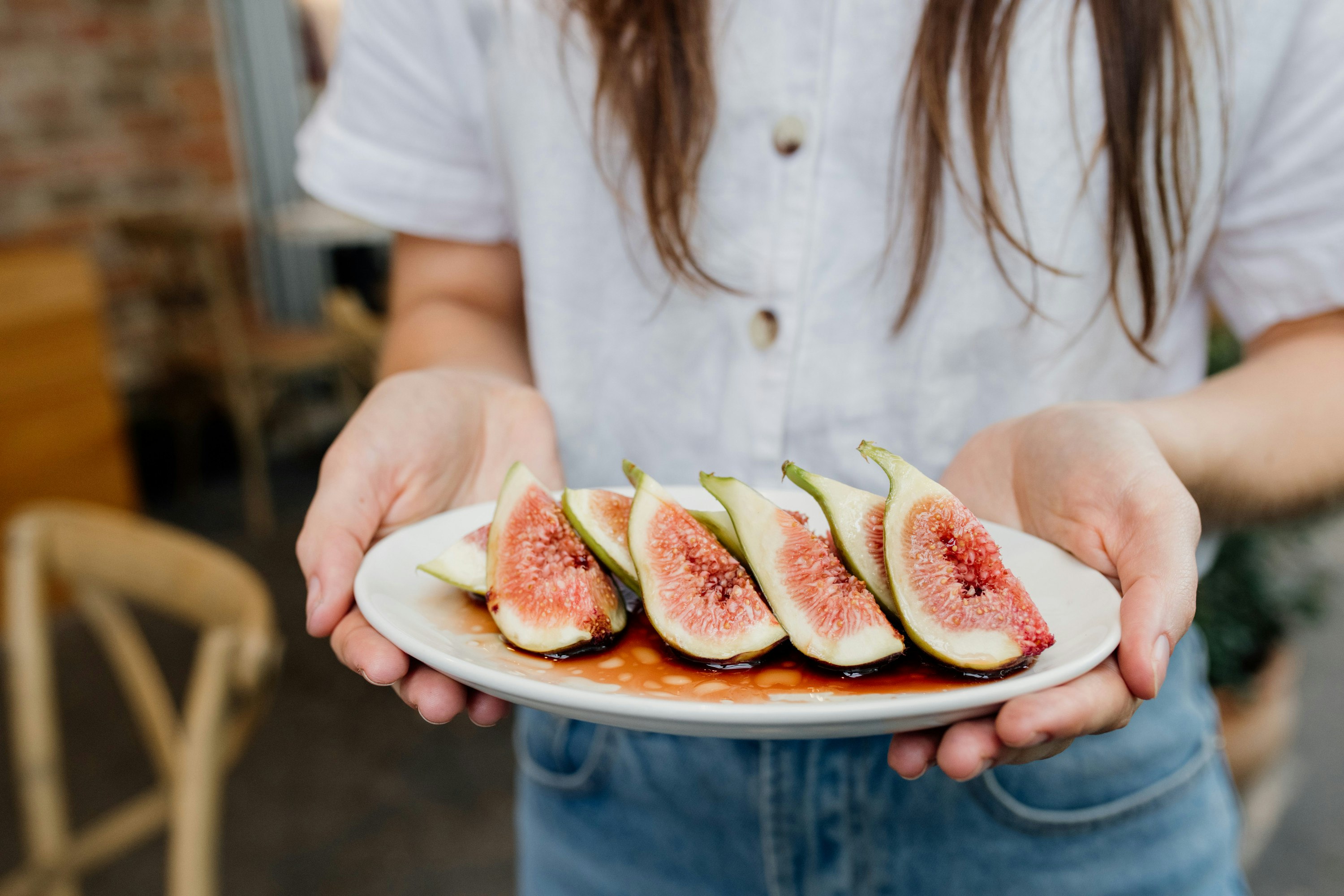 someone holding a plate of cut up figs